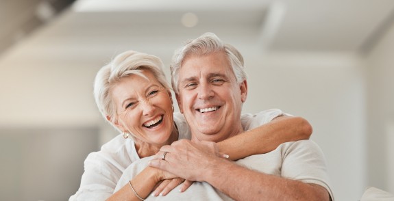 Seniorin umarmt Mann von hinten auf der Couch