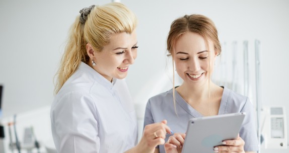 Zahnärztin und ZFA schauen in ein Tablet